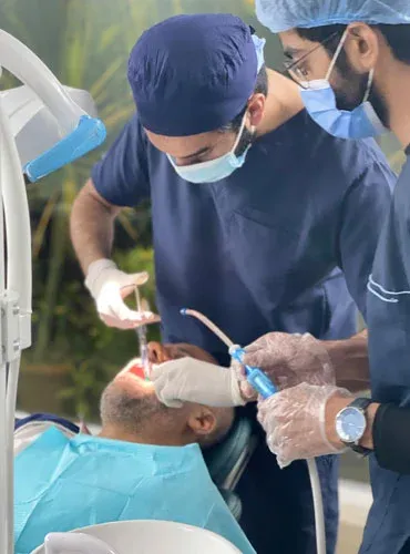 A dentist in surgical cap and mask treating a patient