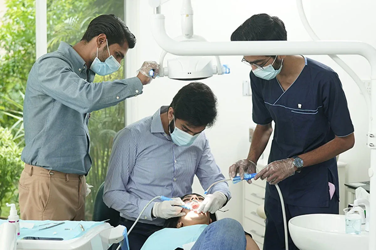 A dentist treating a patient with an assistant beside the chair